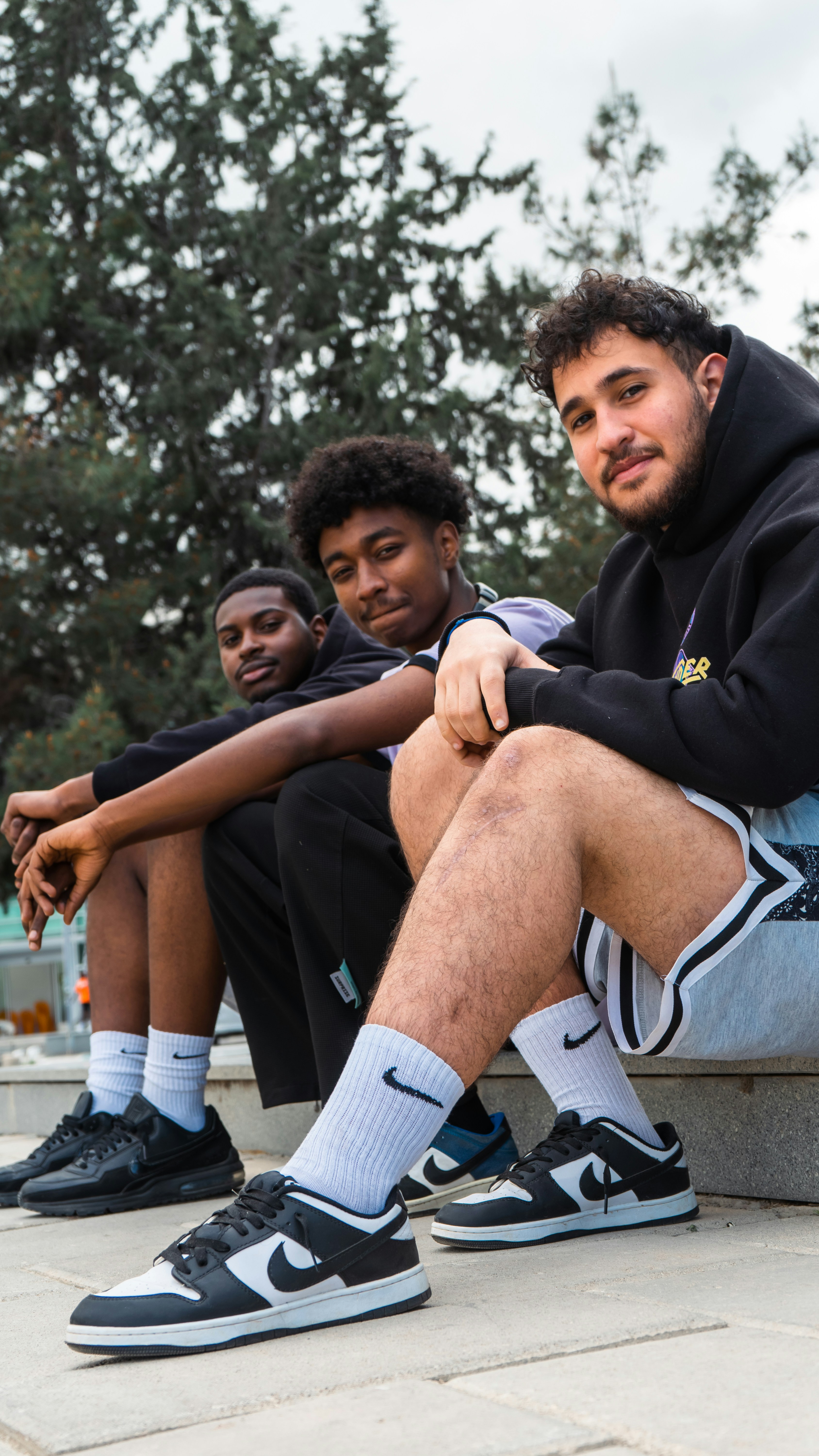 three teens sitting on an edge